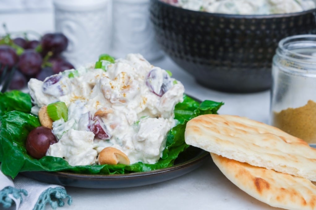 Curried chicken salad on lettuce and pita bread on the side ready to eat. 