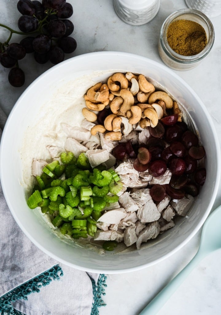 Ingredients to make curried chicken salad in a mixing bowl before combining all ingredients. 