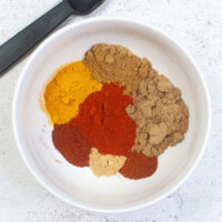 Spices in a white bowl for curry powder seasoning mix.