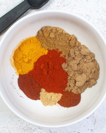 Spices in a white bowl for curry powder seasoning mix.