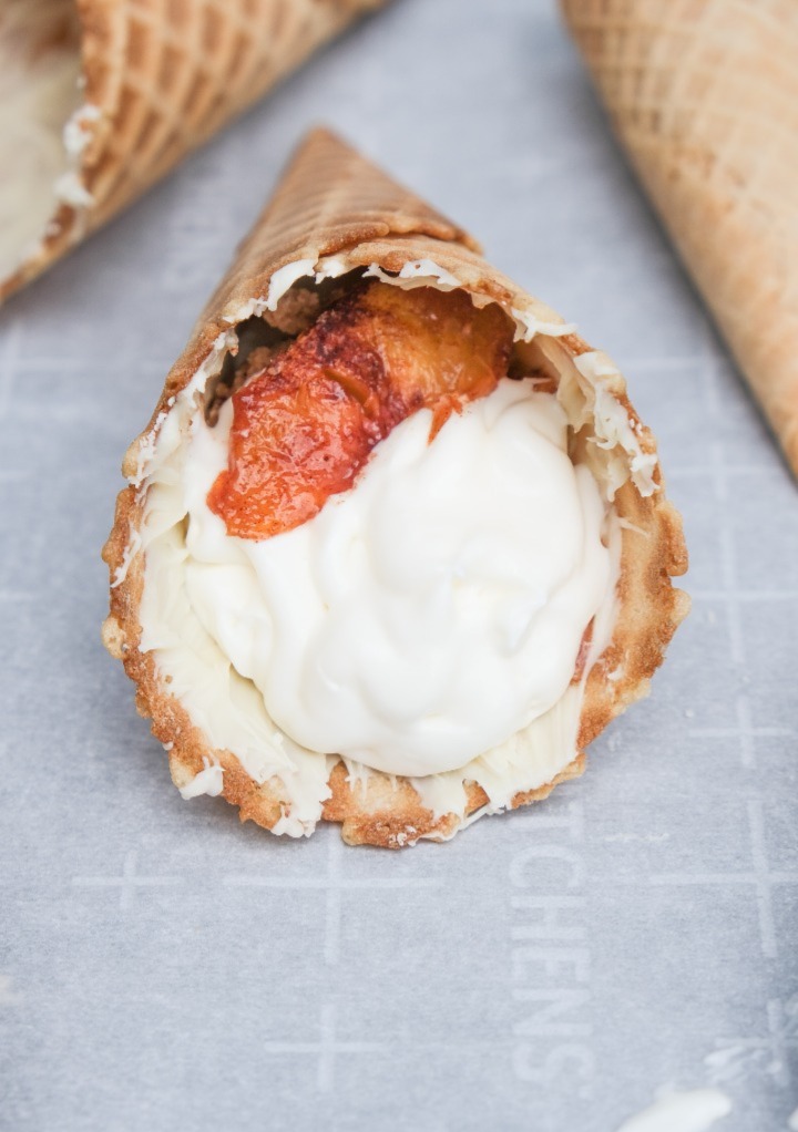 Layering the peach cobble and cheesecake in the center of a waffle cone. 