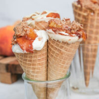 Three sugar cones in a small glass filled with cobbler and cheesecake ready to eat.