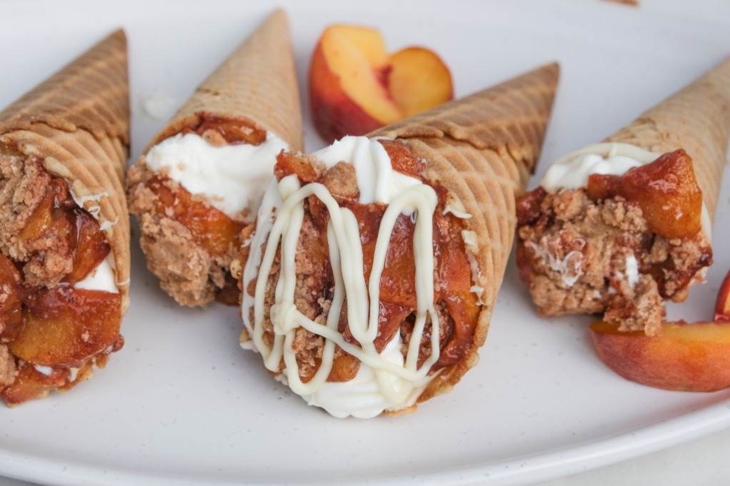 Ice cream waffle cones filled with cobbler and topped with melted white chocolate. 