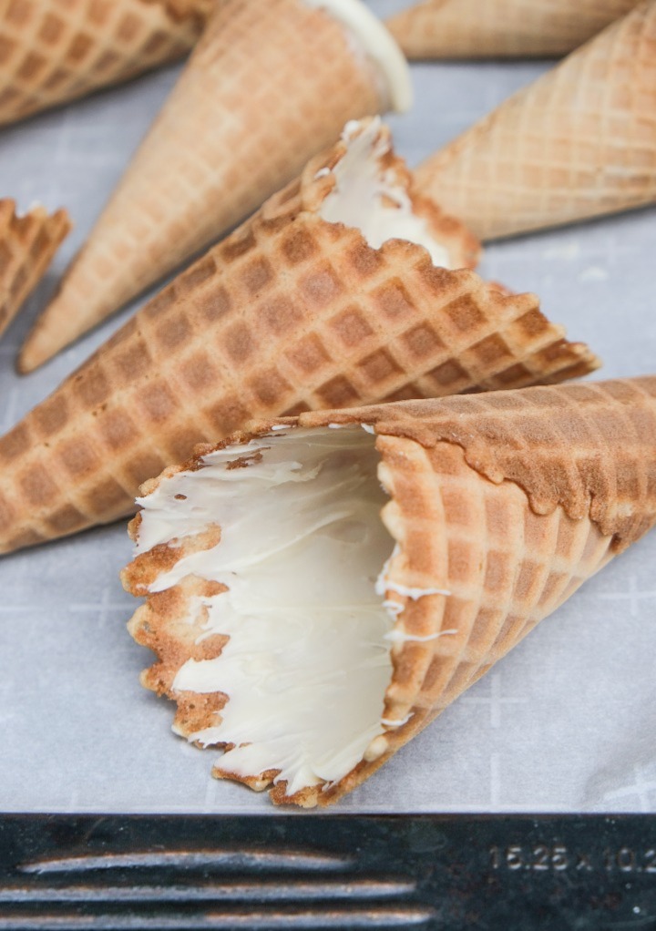 Chocolate coated waffle cones on a baking sheet lined with parchment paper. 