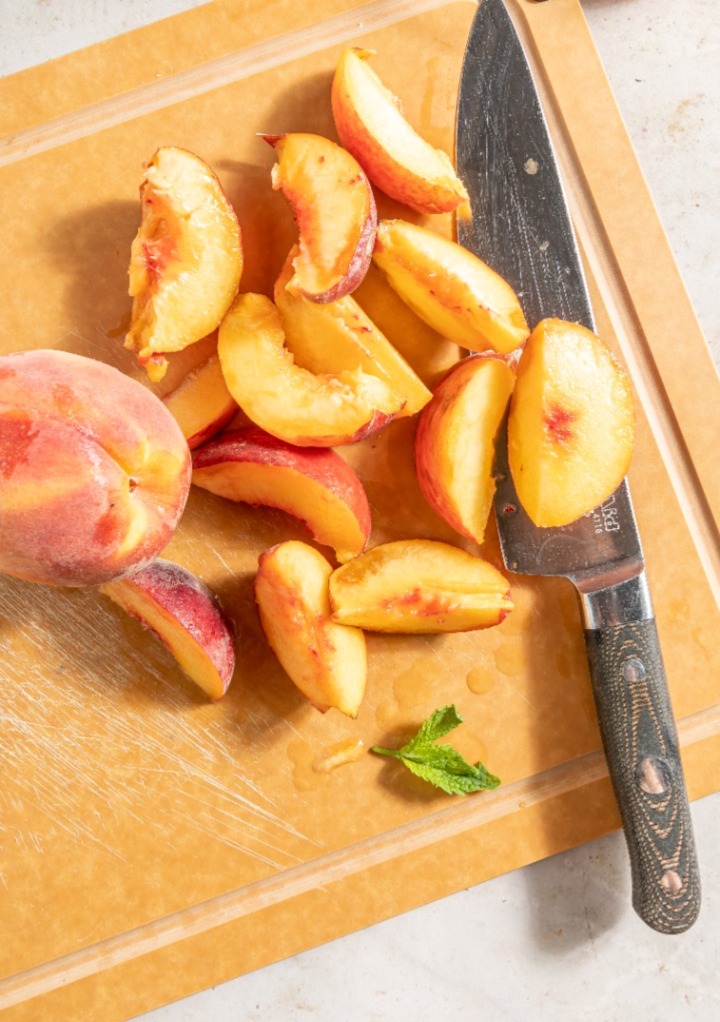 Sliced peaches on a wooden cutting board. 