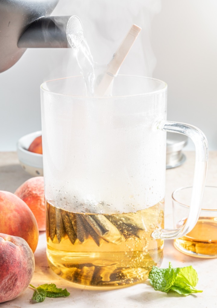 Hot water added to a glass pitcher with tea bags to steep the tea. 