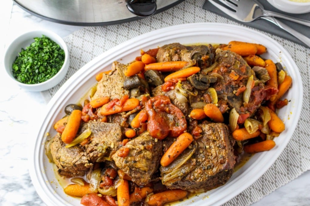 Pot roast on a white serving dish ready to serve.