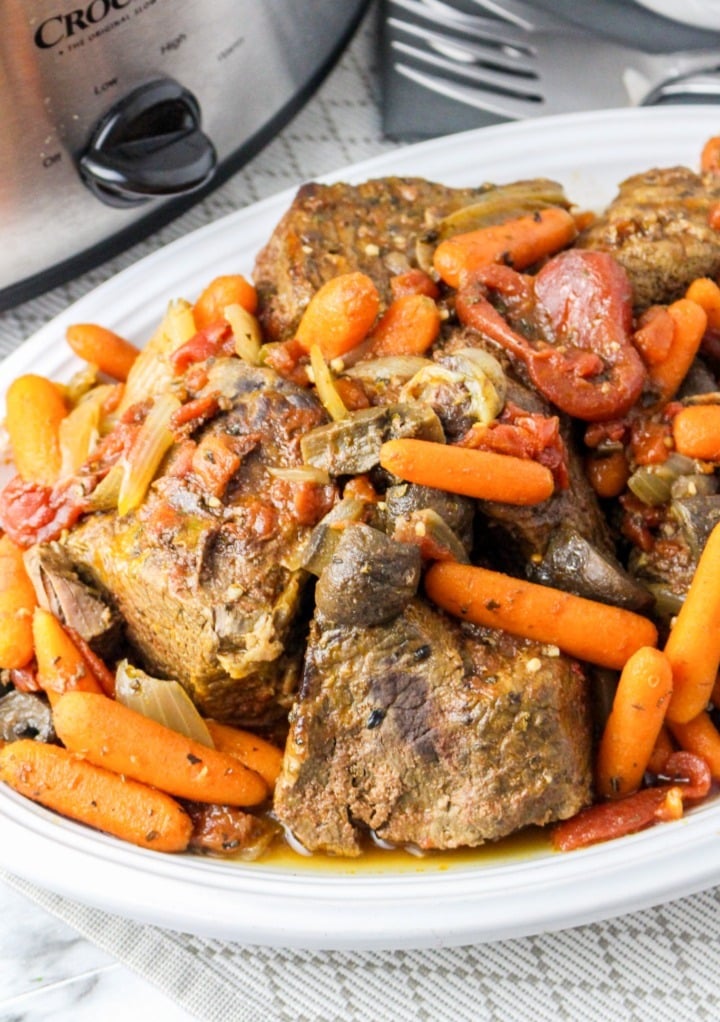 Pot roast on a white serving dish cooked from a slow cooker. 