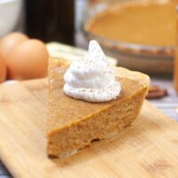 A slice of sweet potato pie topped with whipped cream.