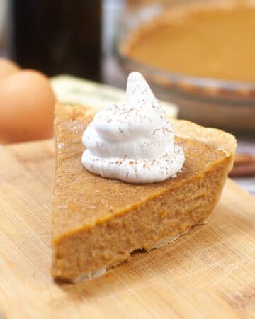 A slice of sweet potato pie topped with whipped cream.