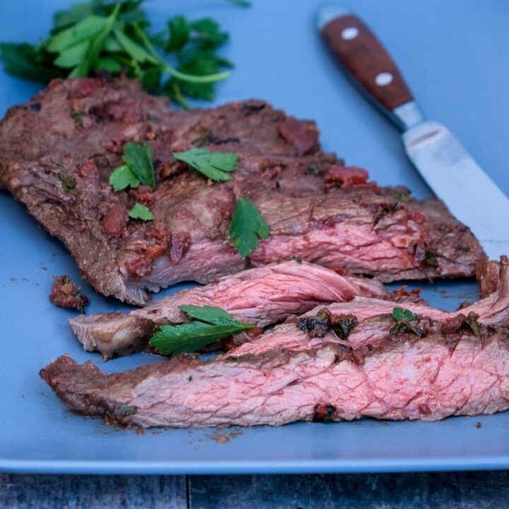 Steak sliced on a blue serving plate.