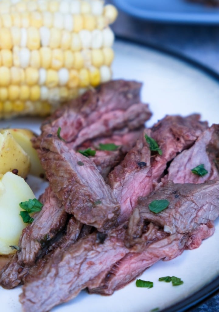 Steak sliced on a white plate with a black rim. 