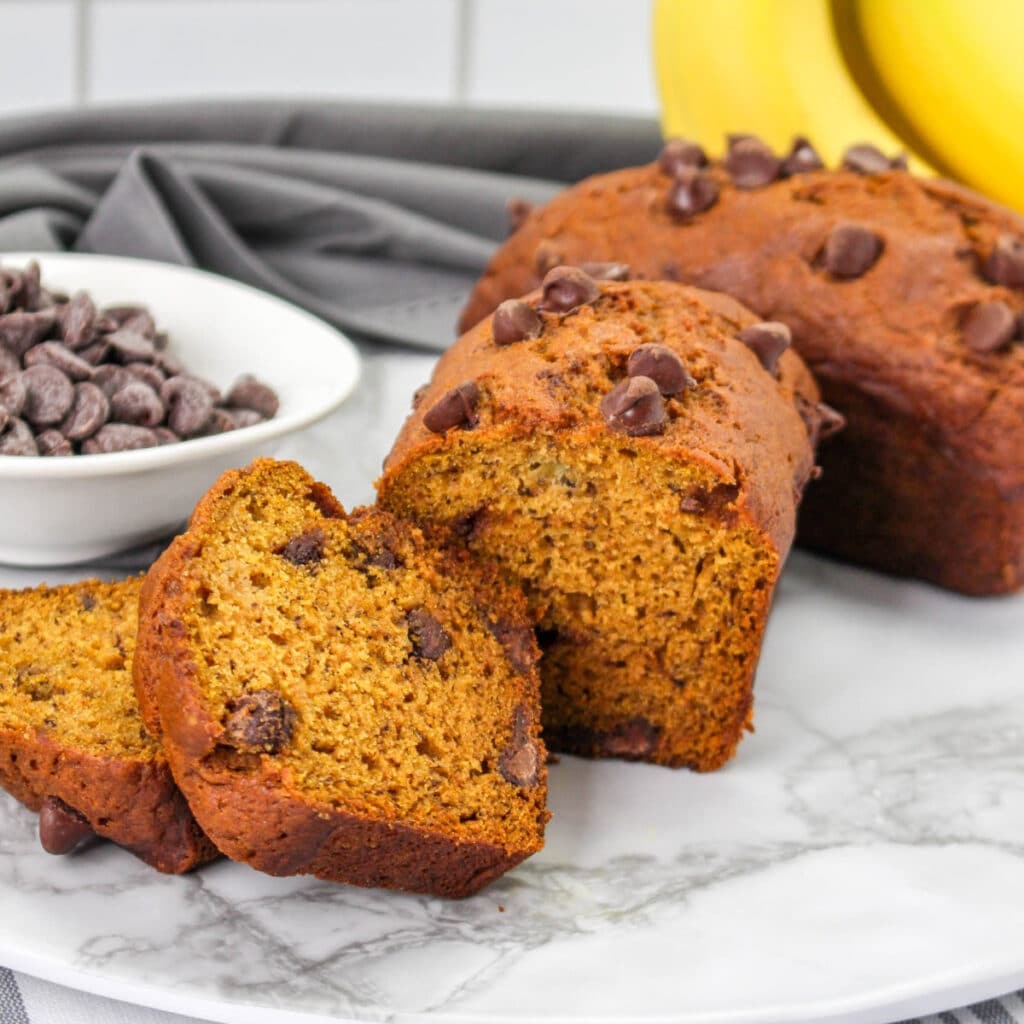 Sliced pieces of low sugar pumpkin bread with chocolate chips on a white cutting board.