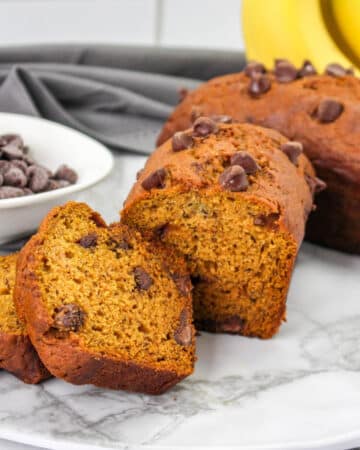 Sliced pieces of low sugar pumpkin bread with chocolate chips on a white cutting board.