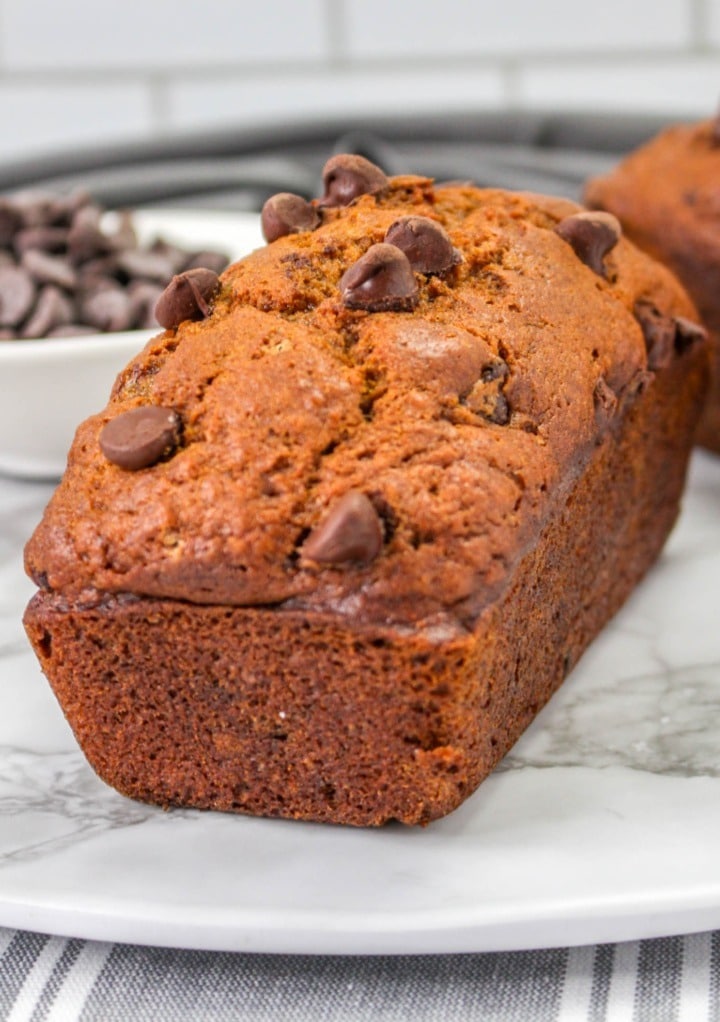 Baked pumpkin bread on a white granite serving dish. 