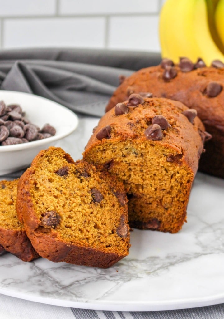 Pumpkin bread with banana and chocolate chips sliced on a marble cutting board. 