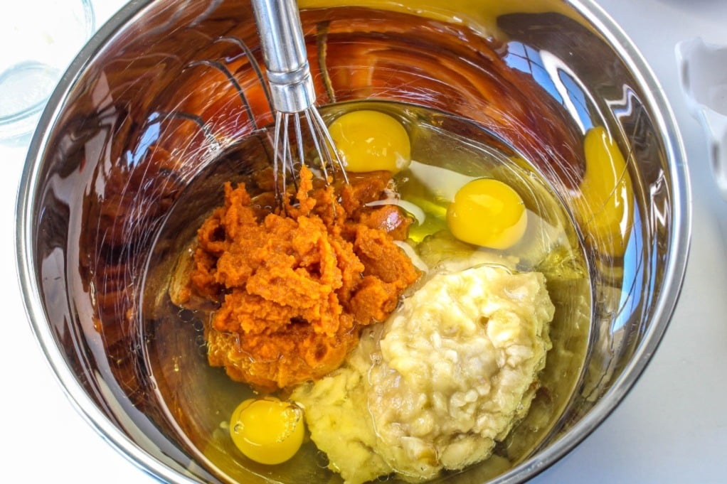 Pumpkin puree in a mixing bowl with eggs and bananas. 