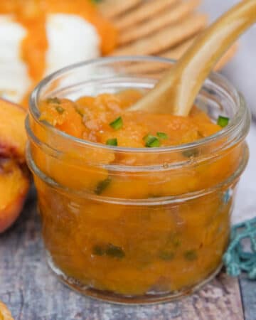 Low sugar peach jam with jalapenos in a small mason jar.