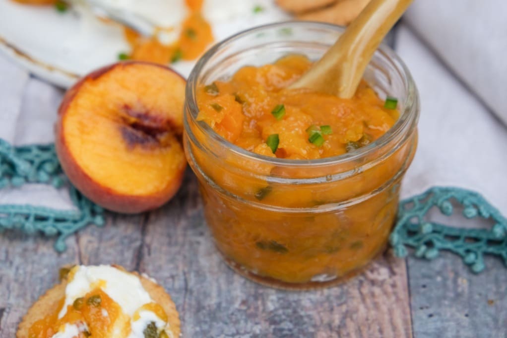 Fresh low sugar peach jam with jalapenos in a mason jar. 