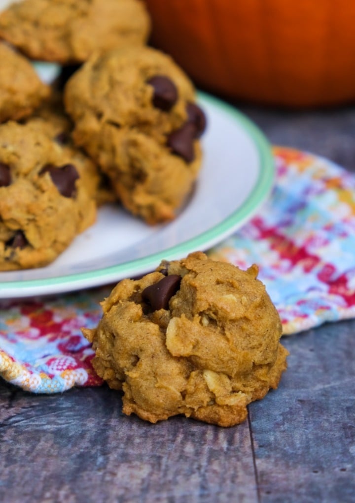 A pumpkin oatmeal cookie on the side of a plateful of cookies. 