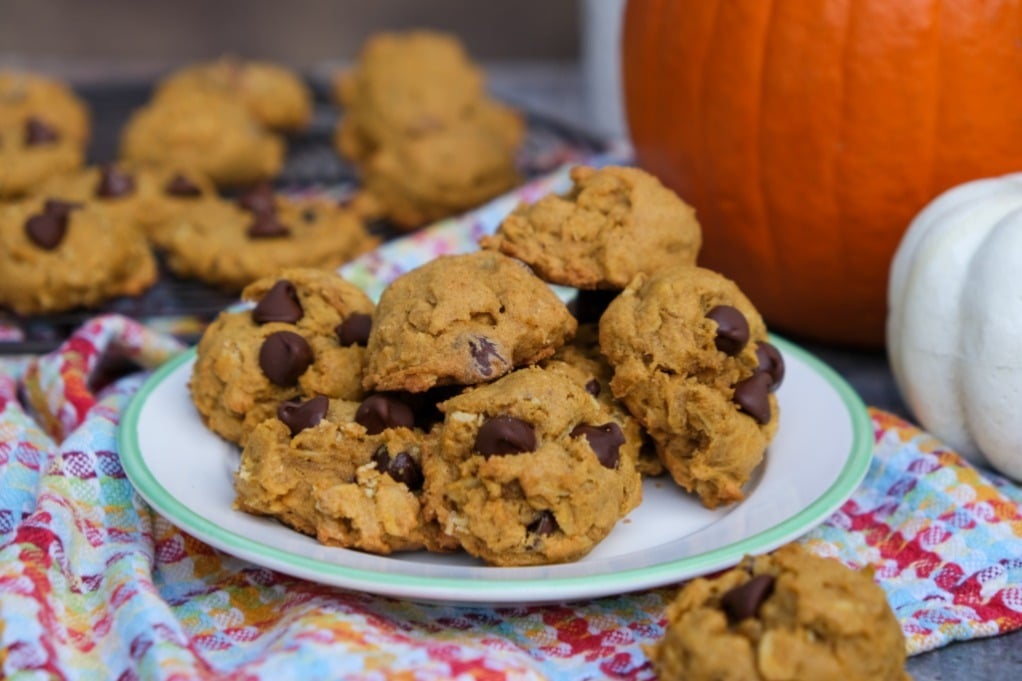 A serving plate of pumpkin oatmeal cookies with a small pumpkin i the background.