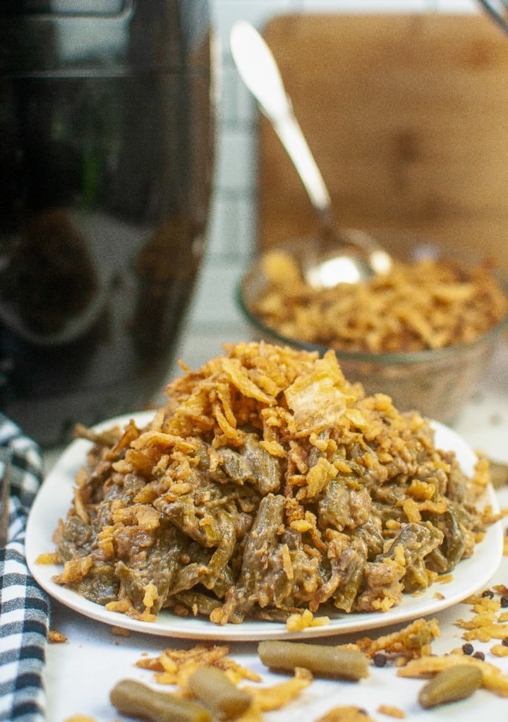 Air fryer green bean casserole dish topped with French fried onions on a white serving plate