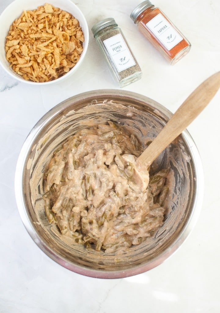 Creamy soup mix folded with green beans is step one when mixing ingredients for a green bean casserole.