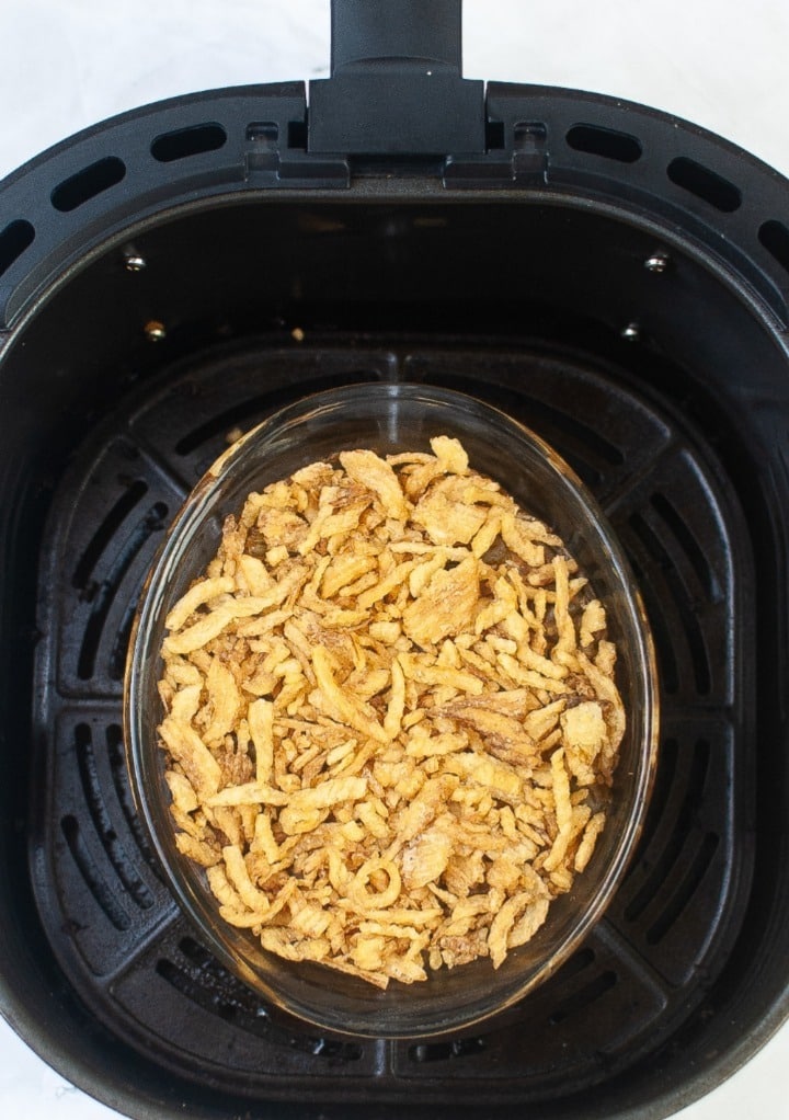 French fried onions topped on green bean casserole cooking in an air fryer. 