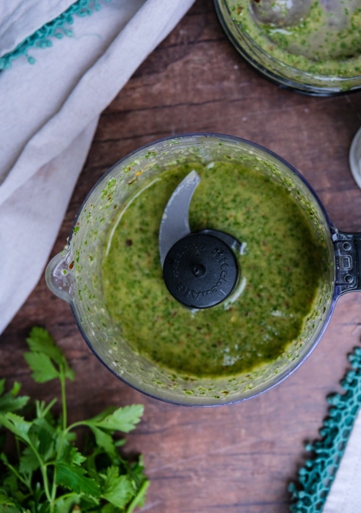 Top view of blended herbs in a mini food processor. 