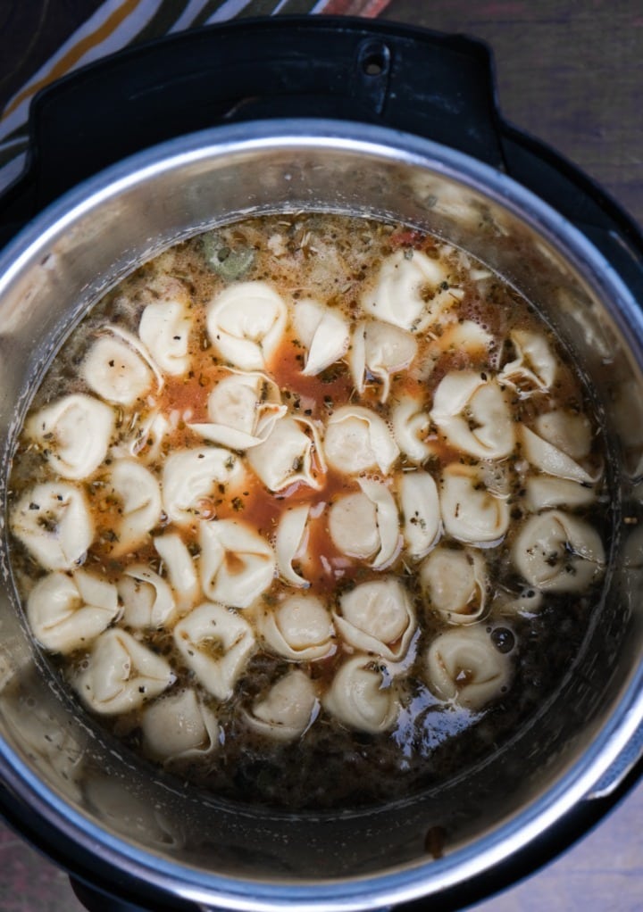 Broth and tortellini in an Instant Pot before cooking. 