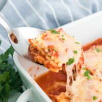 Spoonful of ravioli lasagna from a white serving dish.