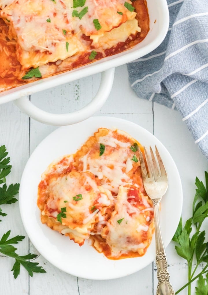 Top view of lasagna on a white plate with a casserole dish on the side. 