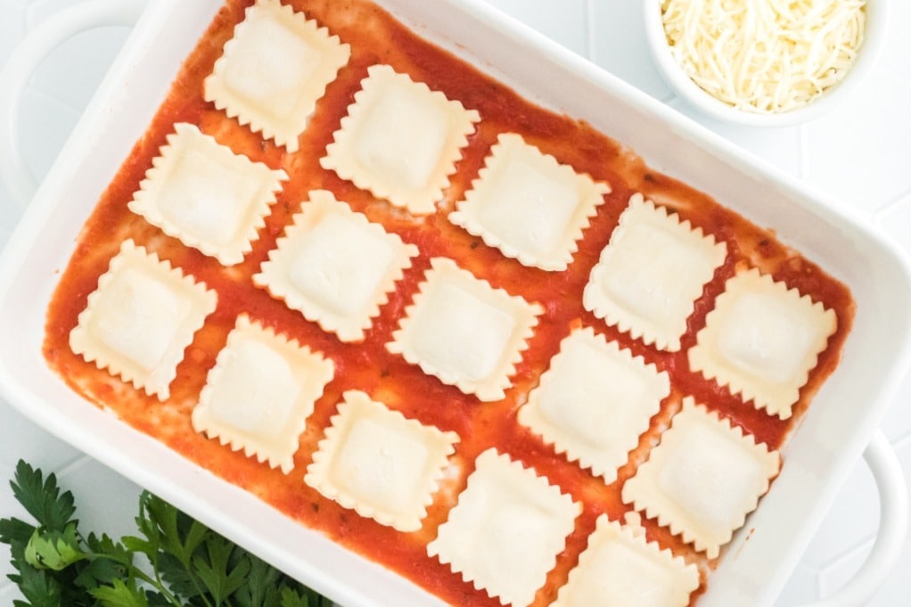 First layer of ravioli lasagna in a white baking dish.