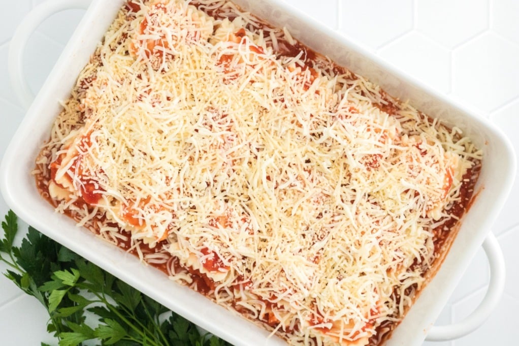 Lasagna layered with pasta and topped with shredded cheese before baking. 