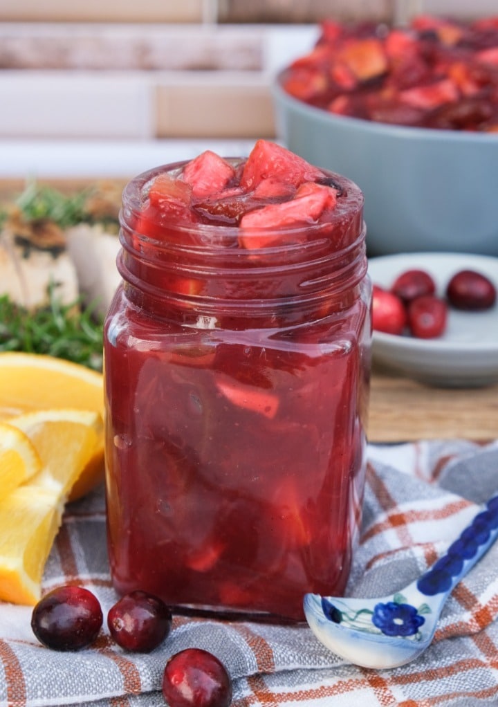 Cranberry chutney with apple and orange in a small glass jar for gift giving. 