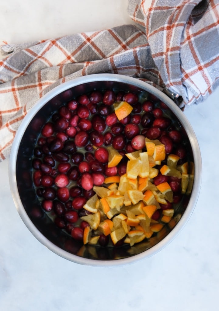 Overhead view of fresh cranberries and diced orange in a saucepan ready to cook.