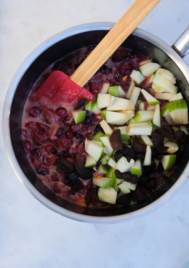 Chopped apples added to cranberry chutney ready to simmer in a saucepan. 
