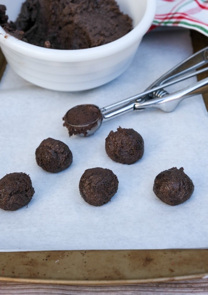 Cookie dough on parchment paper with a cookie scoop.