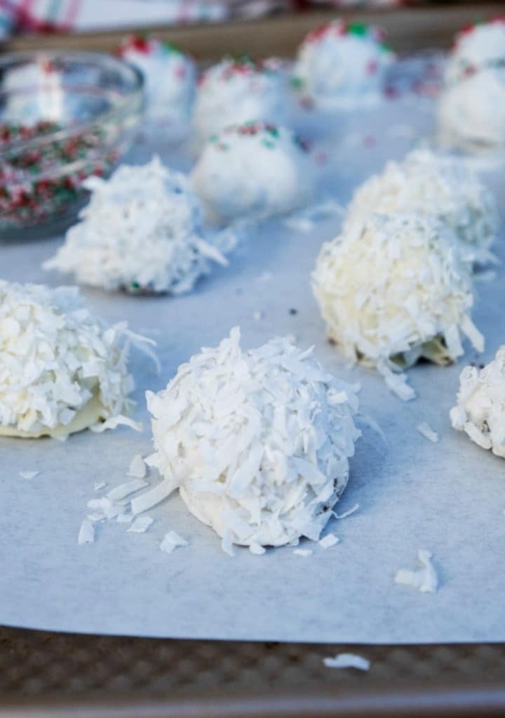 No bake cookies rolled in coconut on a parchment lined cookie tray. 