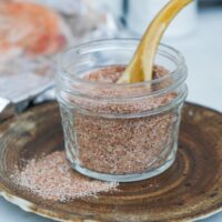 A mix of spices in a small mason jar on a brown plate.