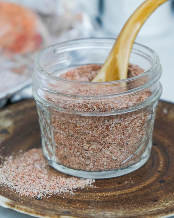 A mix of spices in a small mason jar on a brown plate.