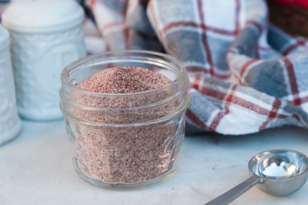 Poultry seasoning spices in a small mason jar with a teaspoon on the side. 