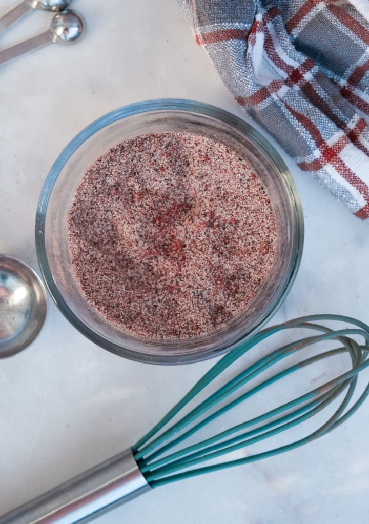 Spices mix together with a small whisk in a clear mixing bowl. 