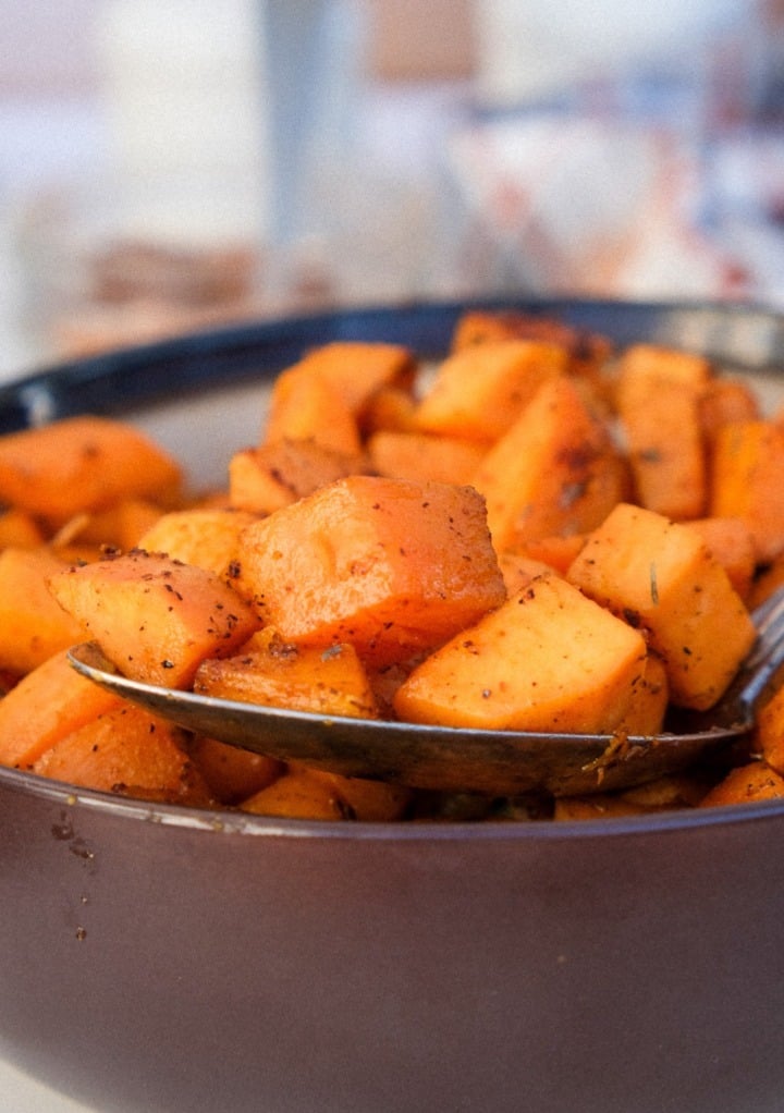 Spoonful of sweet potatoes from a serving bowl. 