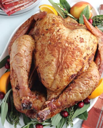 Whole turkey cooked in an electric pellet grill on a white serving platter.