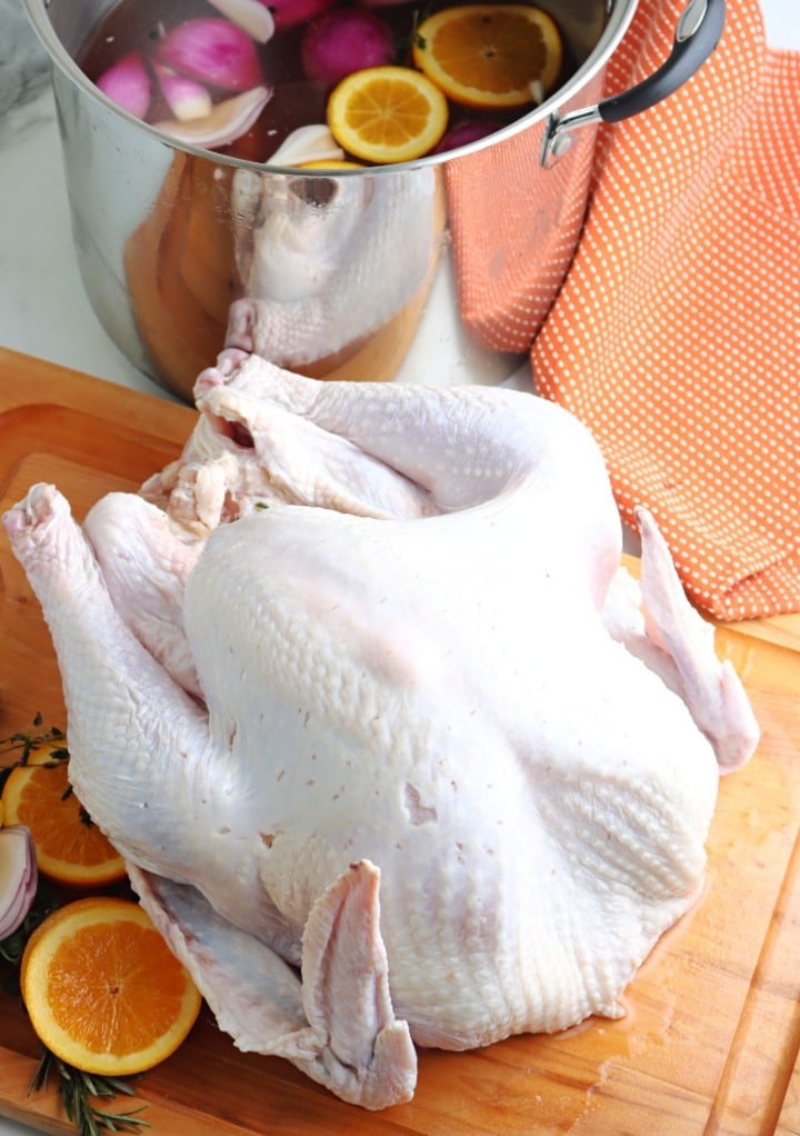 A whole turkey on a cutting board after taking out of a brine solution. 