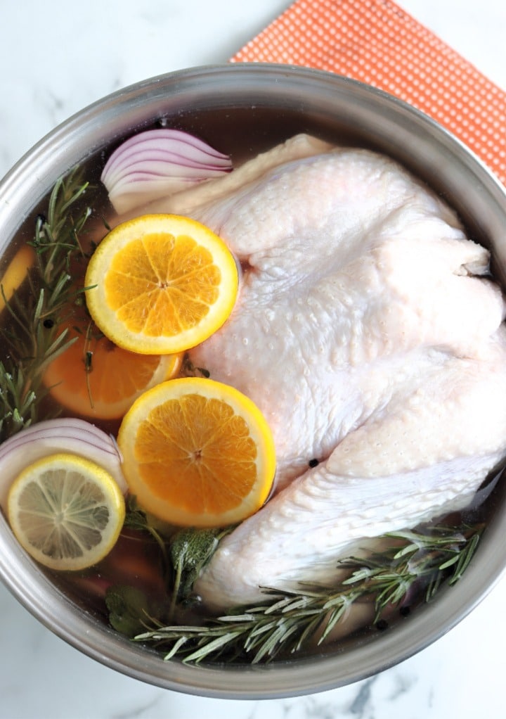 Whole turkey and herbs in a brine solution.