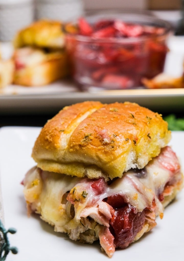 Turkey sliders with cranberry sauce on a white plate. 