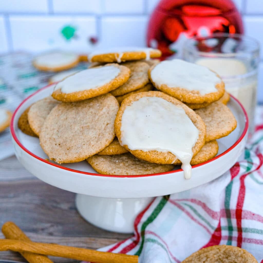 Eggnog cookies plain and a glaze on a white platter with a red rim.