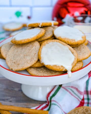 Eggnog cookies plain and a glaze on a white platter with a red rim.